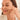 Woman smiling while applying a pimple patch to her cheek for clear, healthy skin.